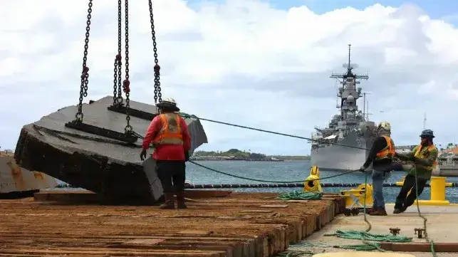 Salvors offload a chunk of a concrete mooring platform removed from USS Arizona (USN)